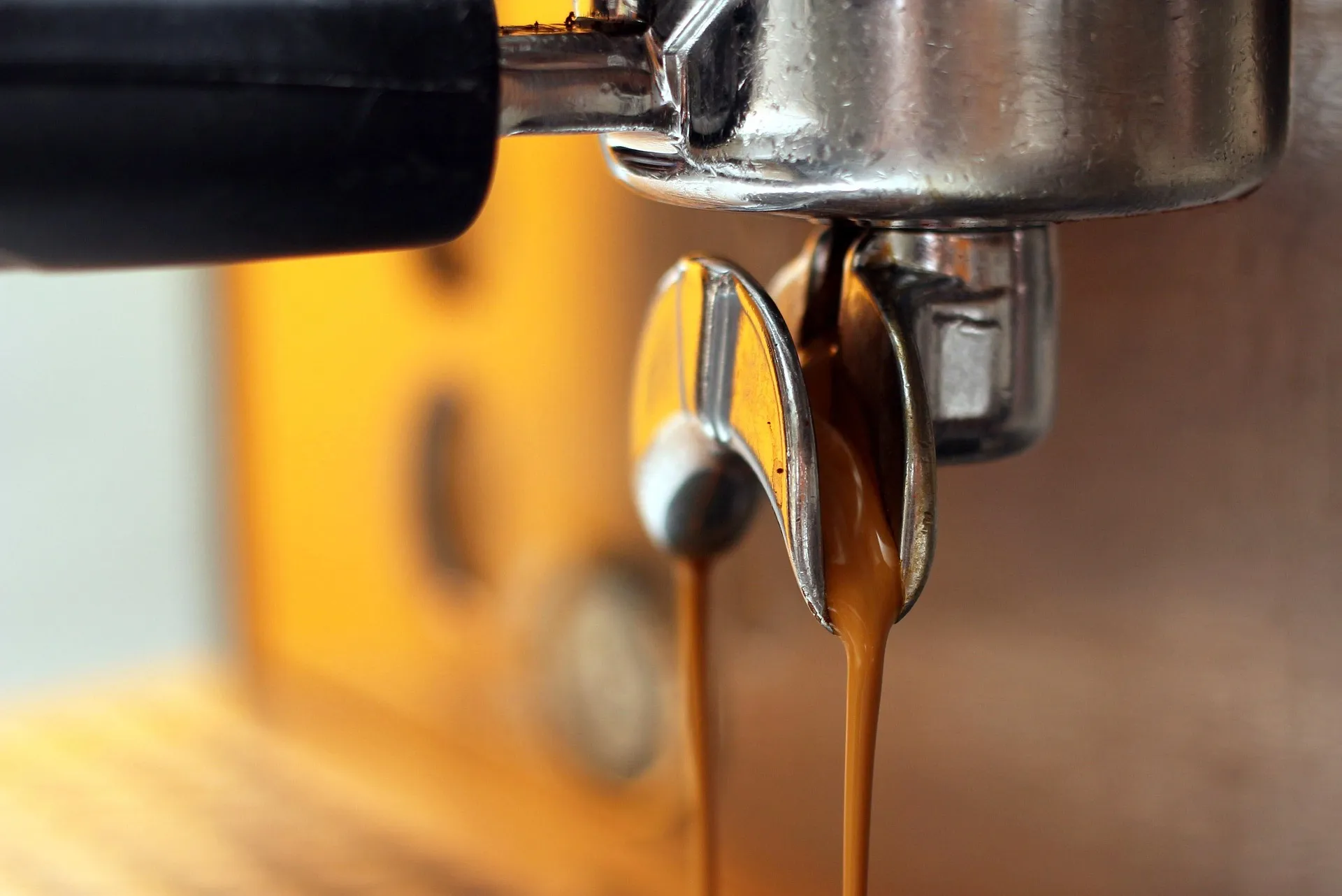 Espresso flowing from the spouts of a portafilter on a coffee machine